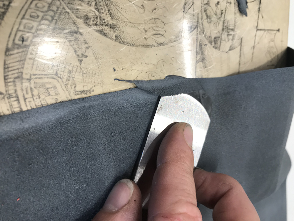 表紙に貼るヤギ革の端を薄く剥ぐ。 表紙の角が革の厚みで凸凹していると、 見返しを貼り付けたとき見栄えが悪くなる。
